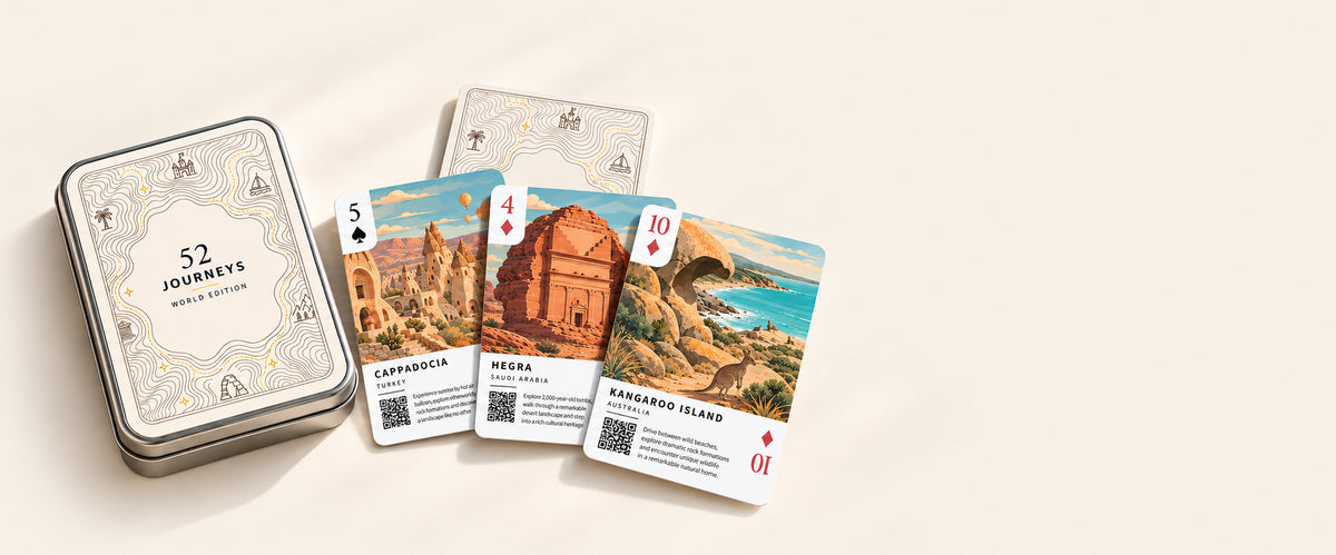 The World Edition tin and illustrated destination cards on a continuous ivory studio surface