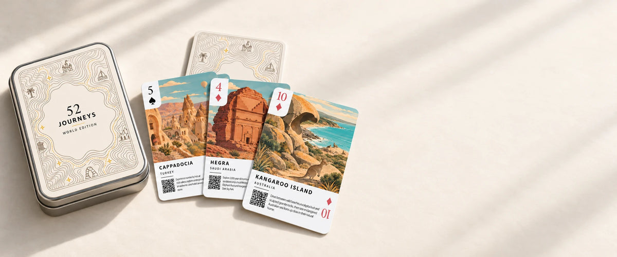 The World Edition tin and illustrated destination cards on a continuous ivory studio surface